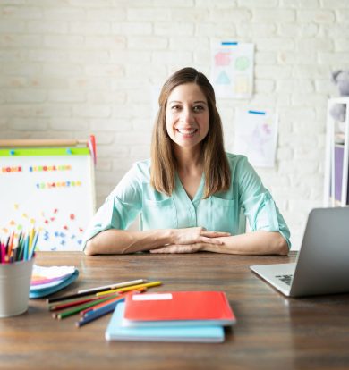 Portrait of a beautiful brunette woman sitting in a desk ready to teach her kids at home